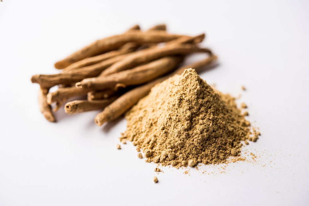 Ashwagandha root powder and dried root pieces on a white background. This adaptogenic herb is known for its stress-reducing and immune-boosting properties.